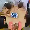 Aerial view looking down on five students gathered around a table looking at scans on a tablet device