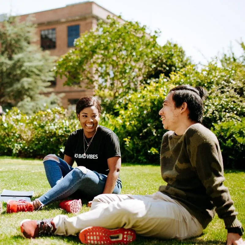 Three female students relax on the grass on a sunny day