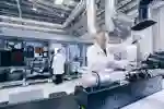 Man in a white coat, gloves and safety glasses works in a lab