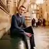 Hull student James Parker wearing a smart suit and sitting on a bench inside the Houses of Parliament.