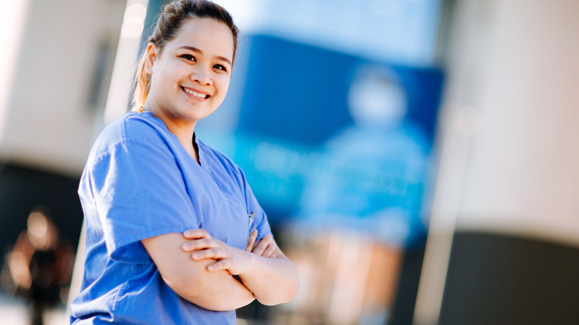 An ODP student in surgical scrubs standing outside the allam medical building
