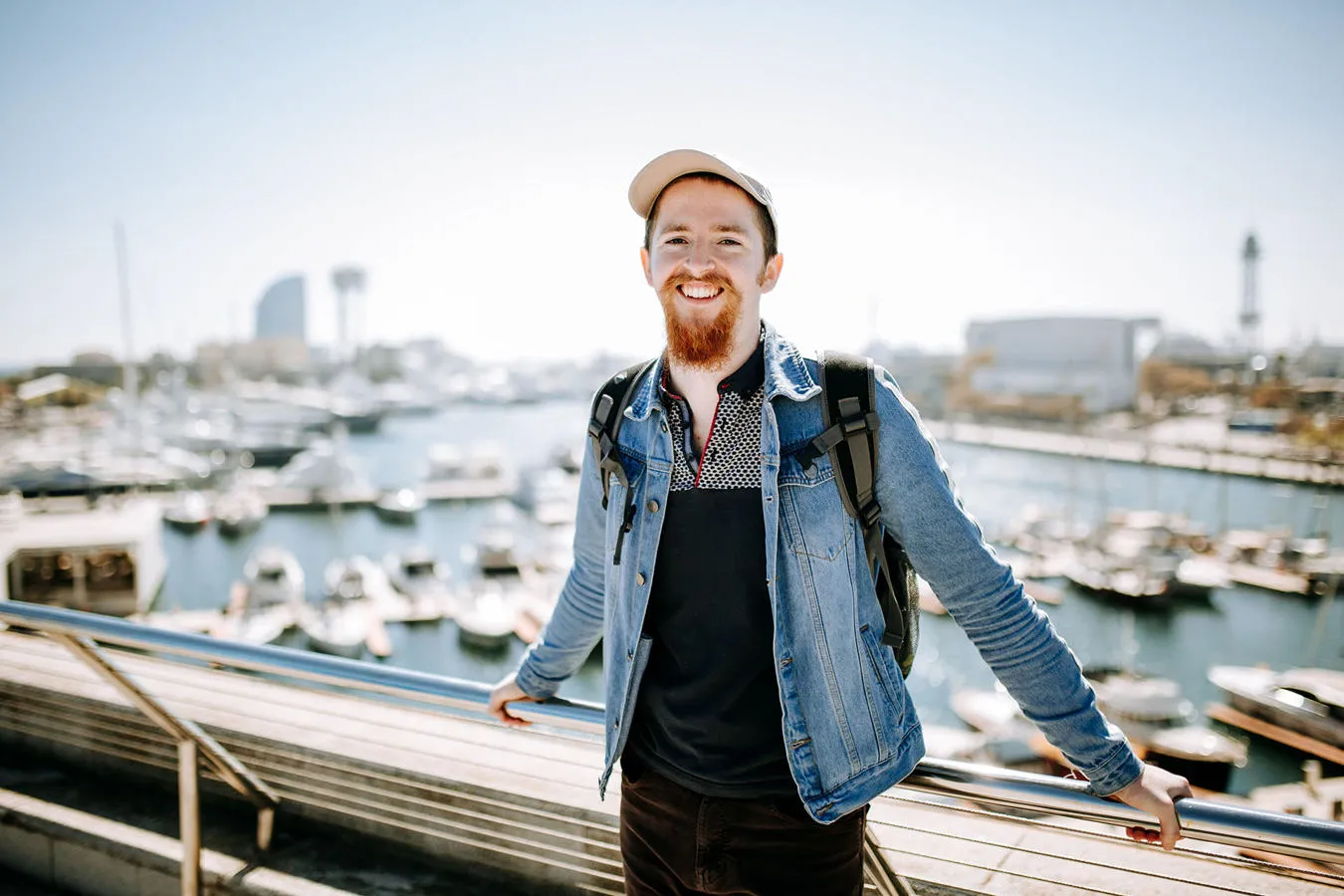 Smiling student leaning against a railing overlooking a harbour