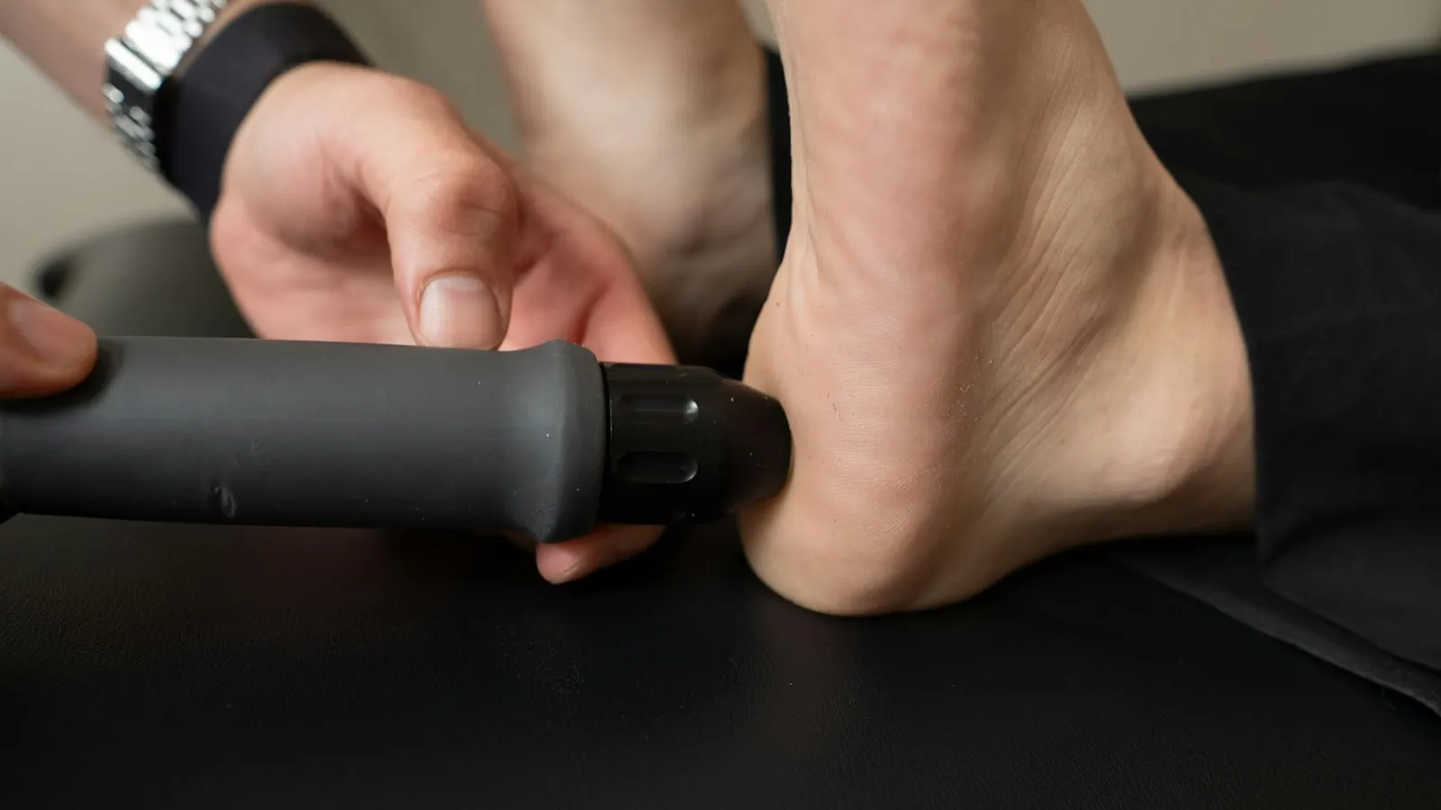 A clinician administering shockwave therapy to a patient with a small black tube