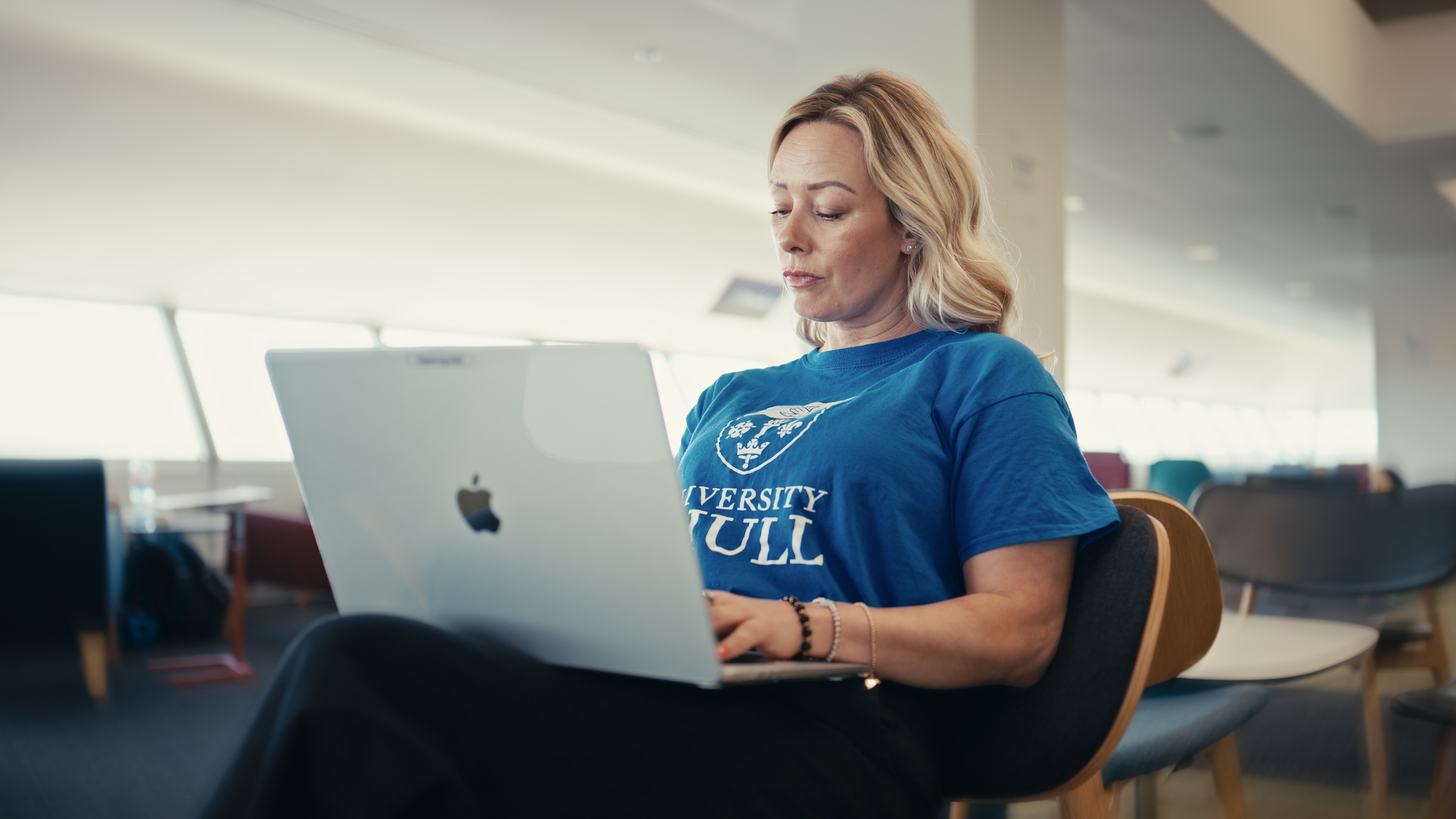 Foundation year student Lara sitting in the library looking at a laptop