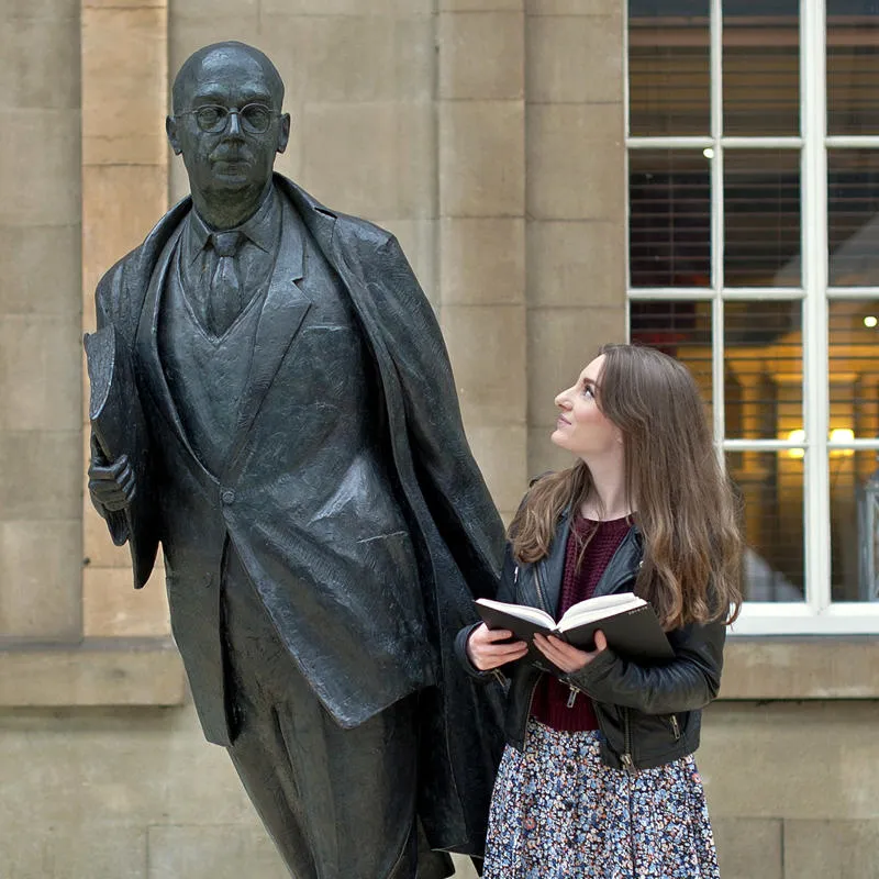 An english student stood with statue of Philip larkin in the city's rail station