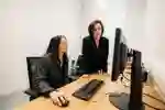 A student uses a computer while an instructor looks on
