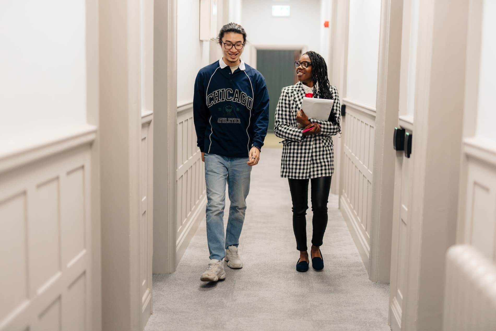 Two students walking down the Legal Advice Centre corridor carrying paperwork