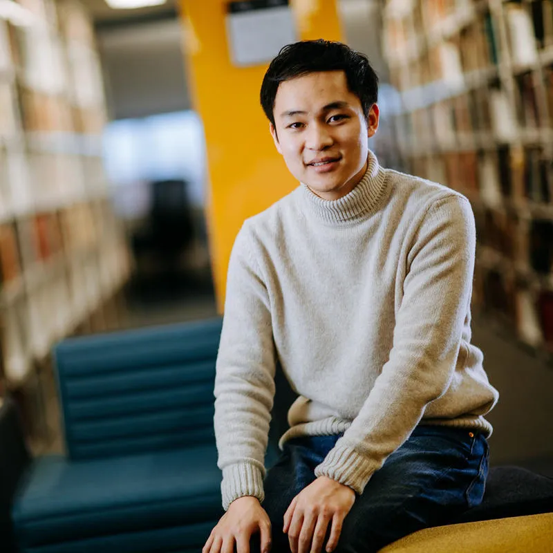 A student sat smiling in the library.