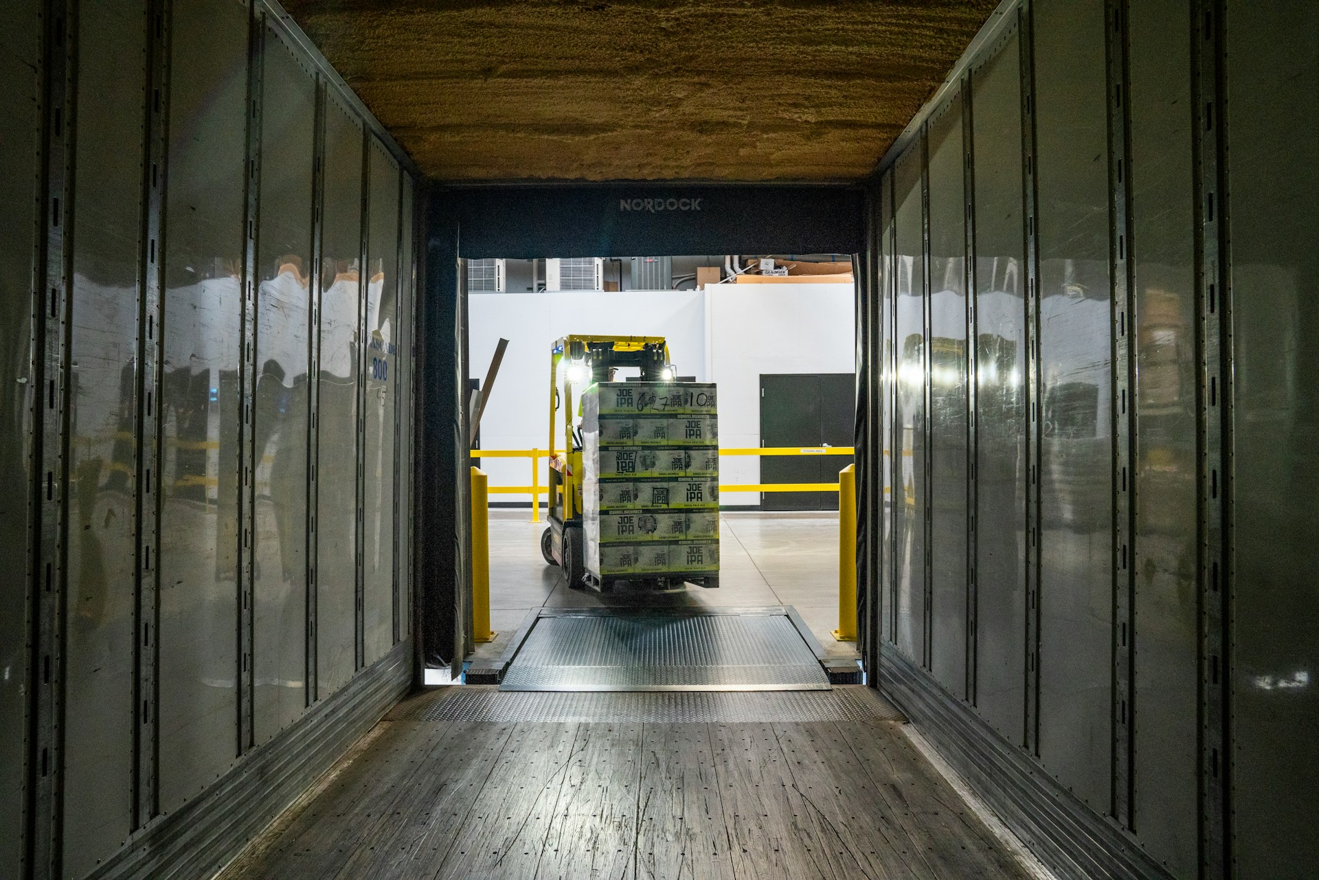 A forklift truck driver reverses from an empty shipping container