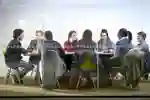 a group of students sat at a large table in a library study room