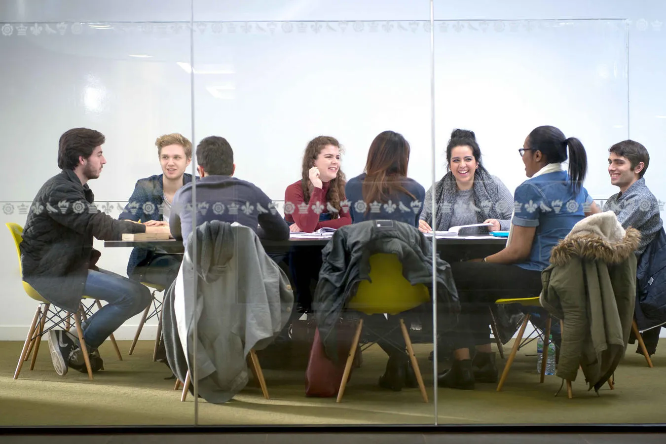A group of students sat at a large table in a library study room