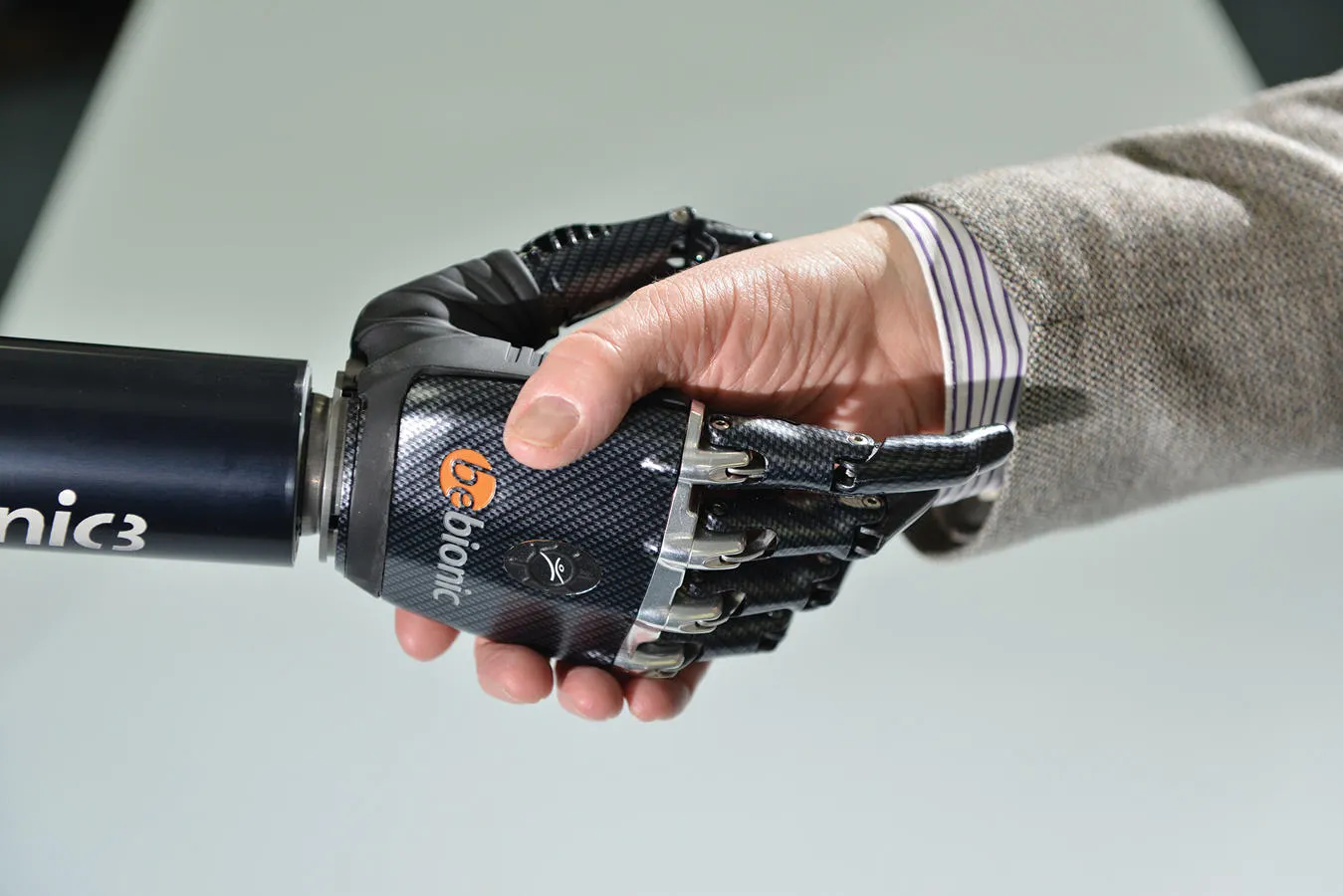 A man in a suit shaking hands with a robotic hand