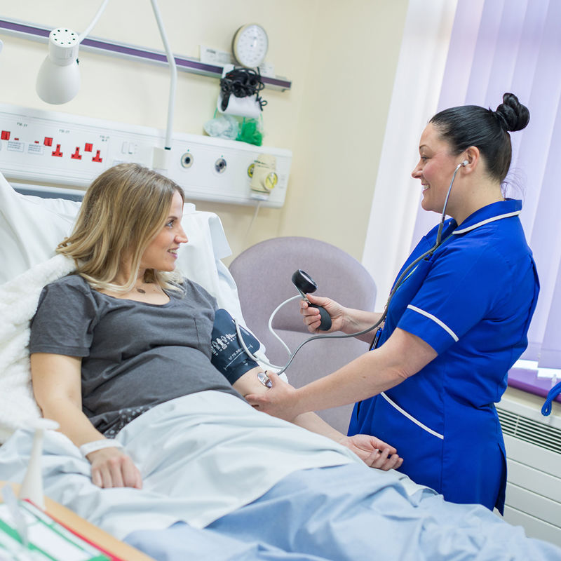 A midwifery student in a ward performing a blood pressure check
