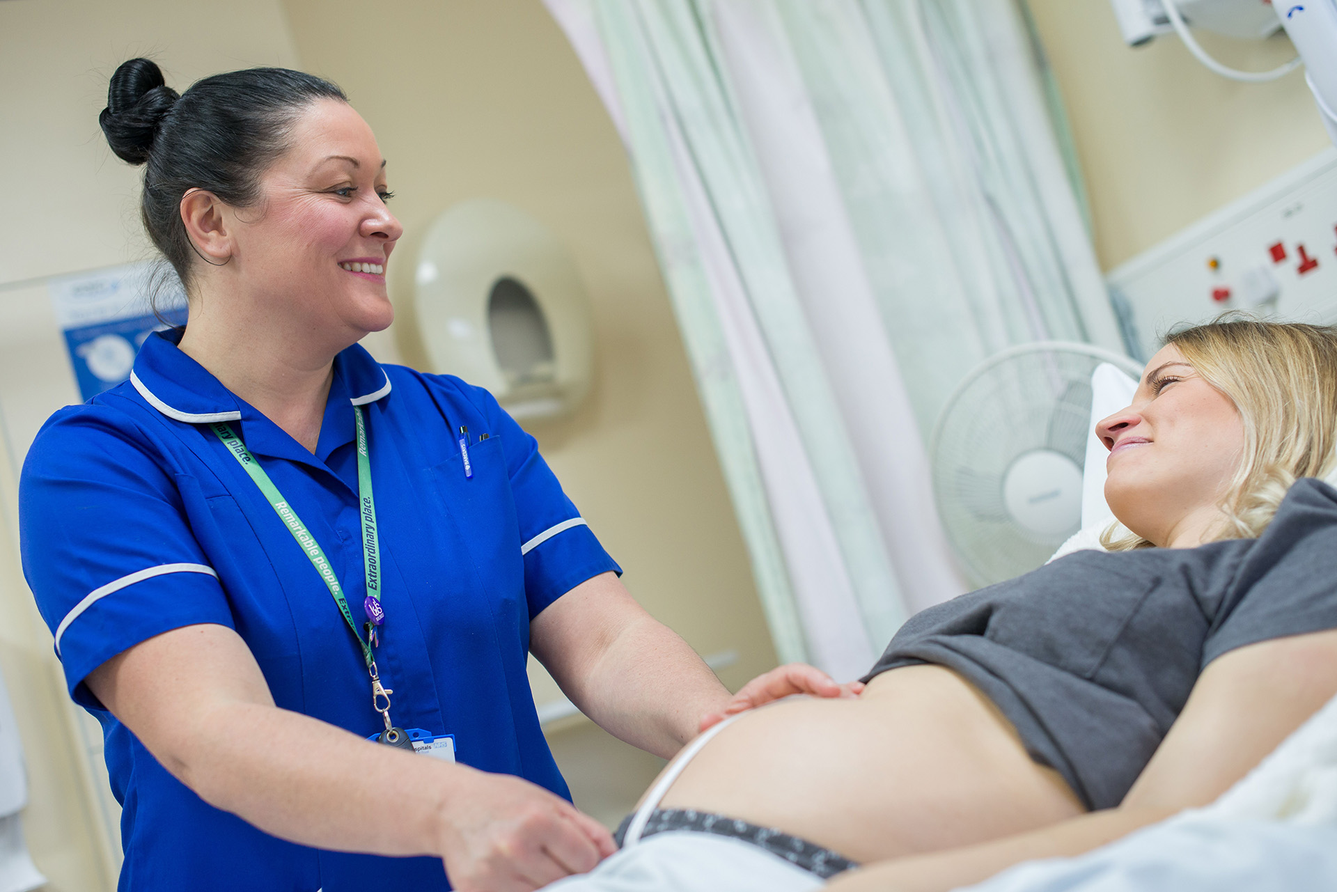 A student midwife stands next to a pregnant patient