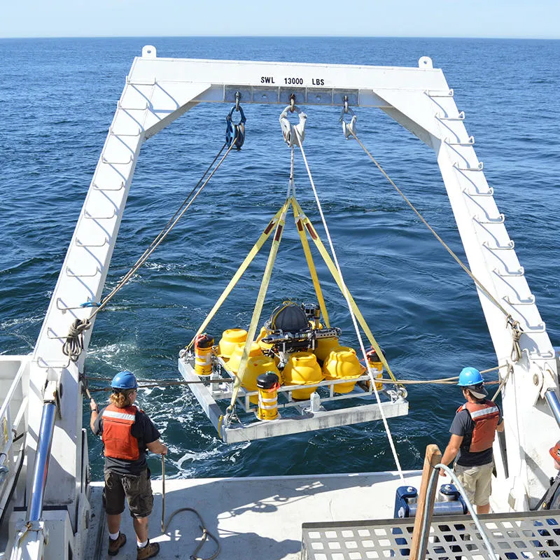 Two researchers raise equipment from the sea using a winch platform