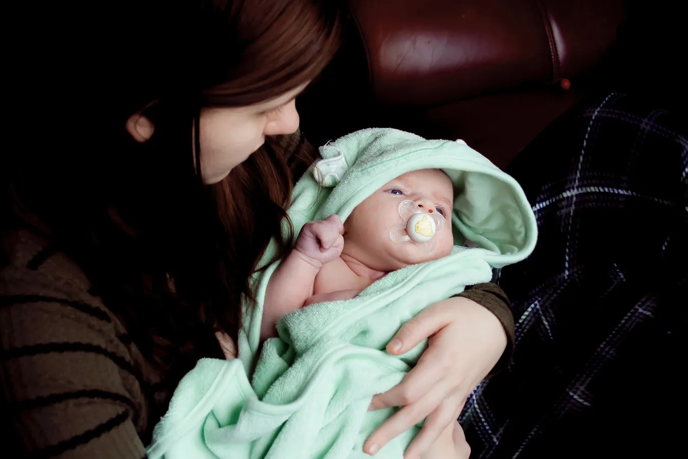 Mother cradling baby wrapped in green blanket