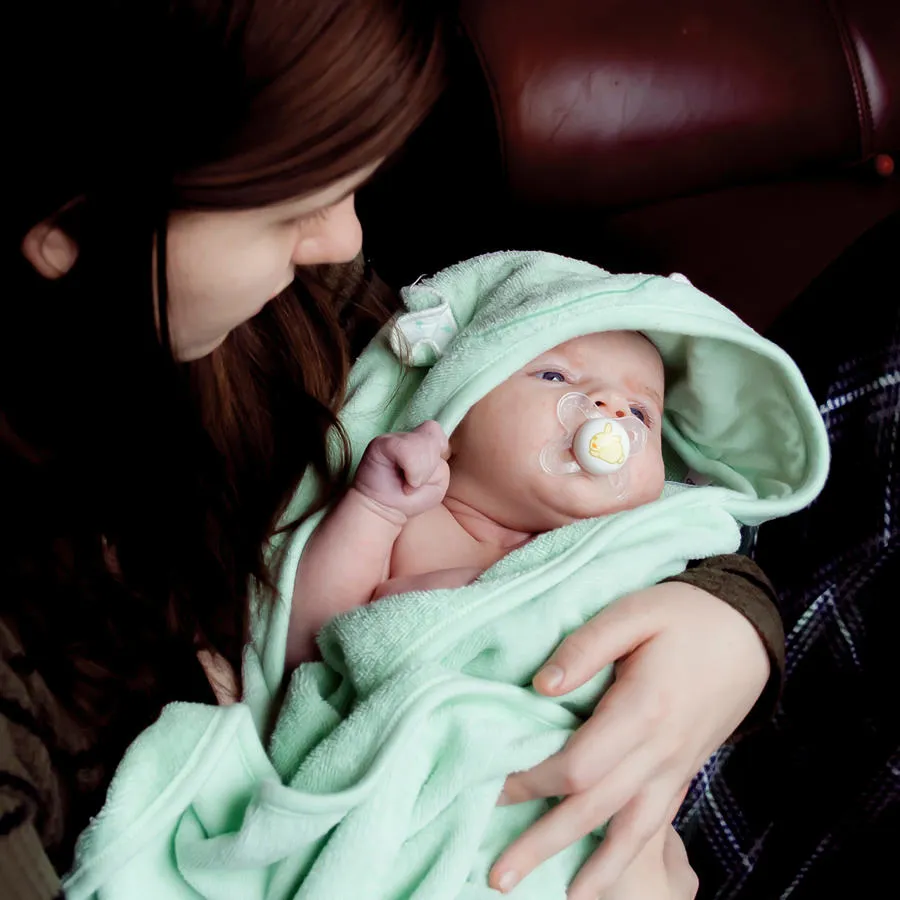 Mother cradling a baby wrapped in a green blanket