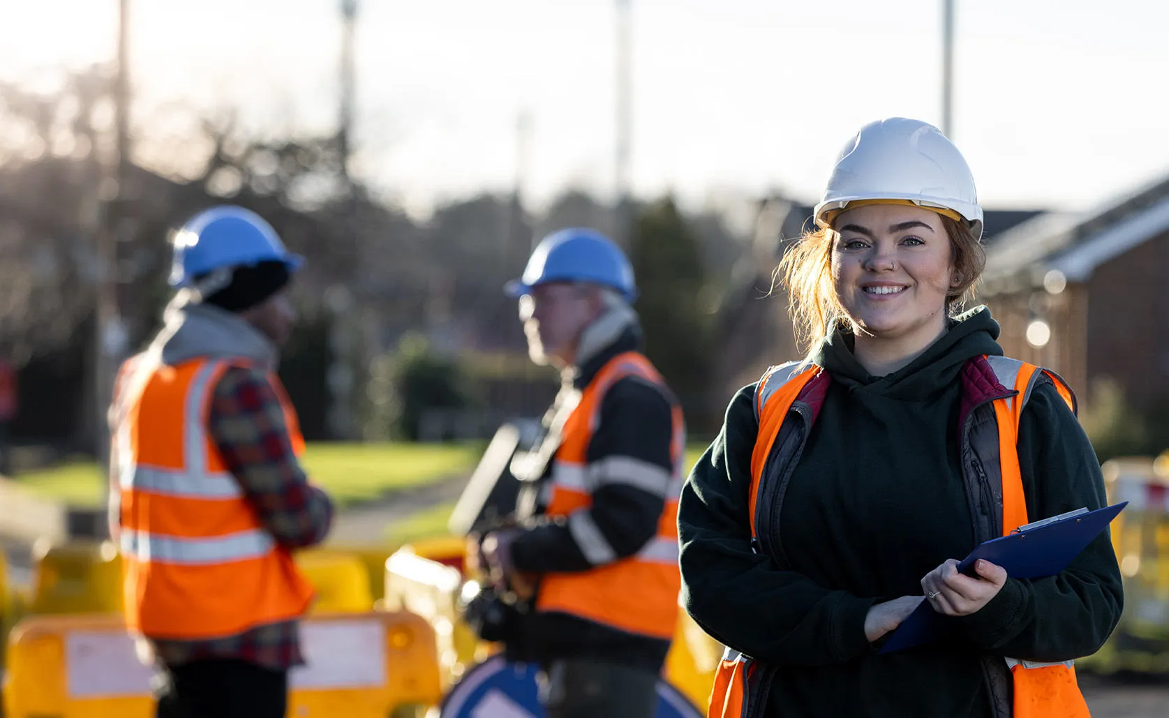 Student in a high viz vest holding a clipboard.