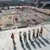 A line of workers wearing high vis clothing stand at a construction site