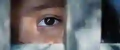 A view of a person's eye looking out between metal bars