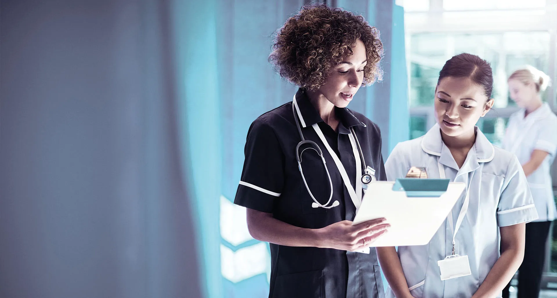 Two nurses reading from a clipboard
