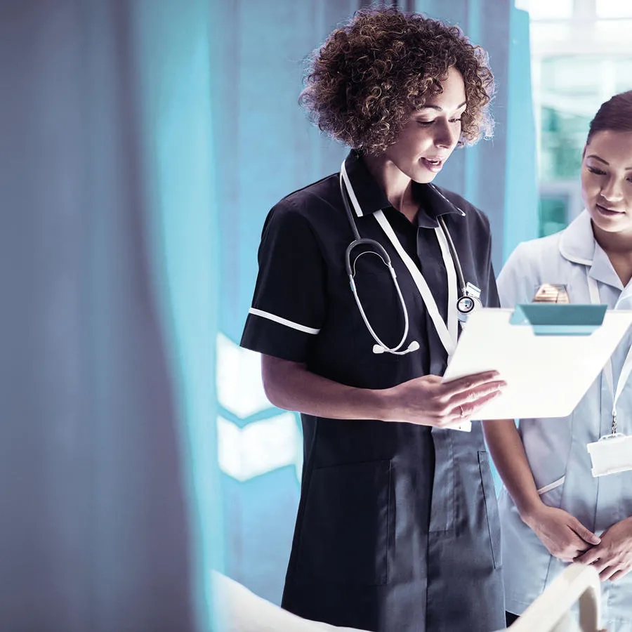 Two nurses reading from a clipboard