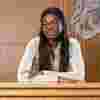 A law student poses in front of the UK royal coat of arms in a mock courtroom