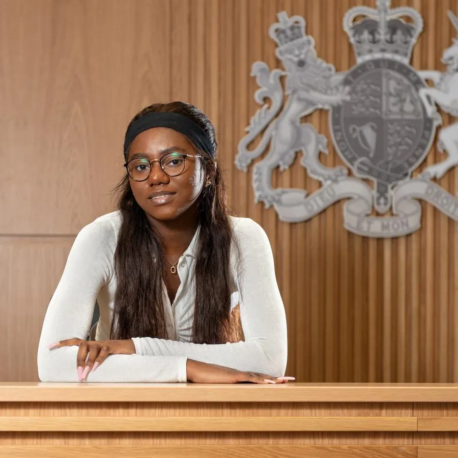 A young woman sat at a bench in a mock courtroom with her arms folded