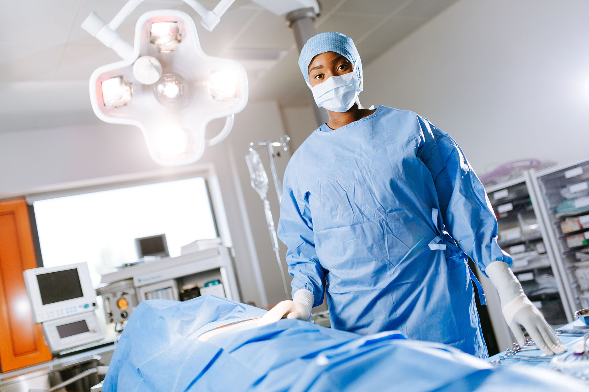 A female student wearing blue scrubs stands in an operating theatre 