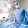 A female student wearing blue scrubs stands in an operating theatre