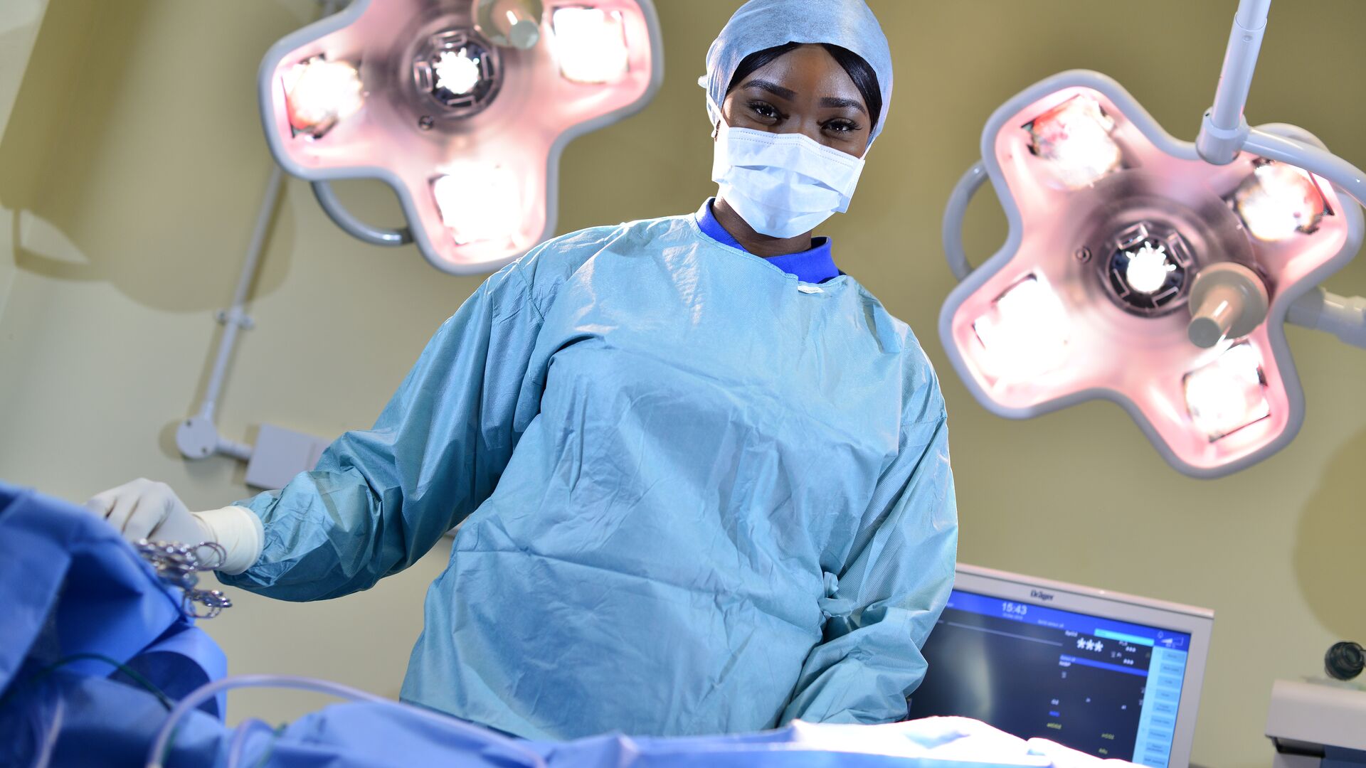 ODP student Olayemi Elizabeth Ajayi stands in scrubs at an operating table under the lights
