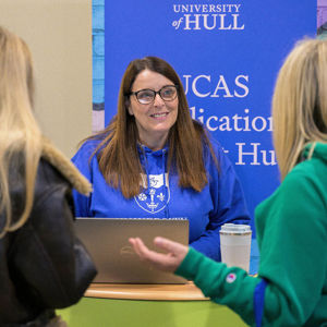 A member of staff greets prospective students on a help stand at an Open Day