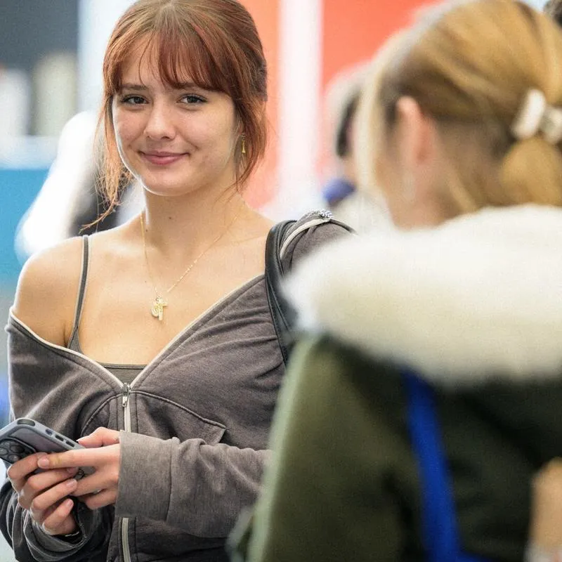 A young student smiling at the camera at an event on campus