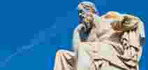 A white statue of Greek philosopher Socrates with a sunny blue sky behind
