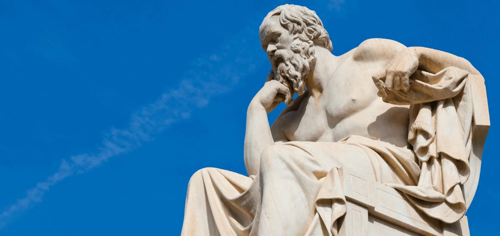 A white statue of Greek philosopher Socrates with a sunny blue sky behind