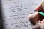 Student writing notes next to an equation