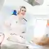 Two student midwives in white uniforms in a simulated neonatal ward