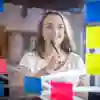 A marketing student smiles while looking at colourful post-it notes on a glass screen