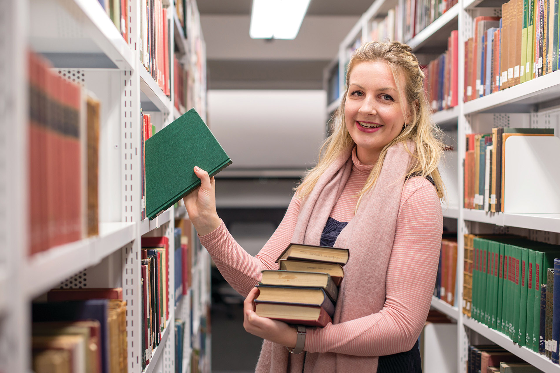Student taking books off the library shelves