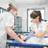 Two children's nurses working with a patient laid on a bed