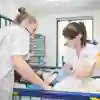 Two children's nurses working with a patient laid on a bed