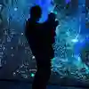 A silhouetted figure before a glowing projection screen of watery images