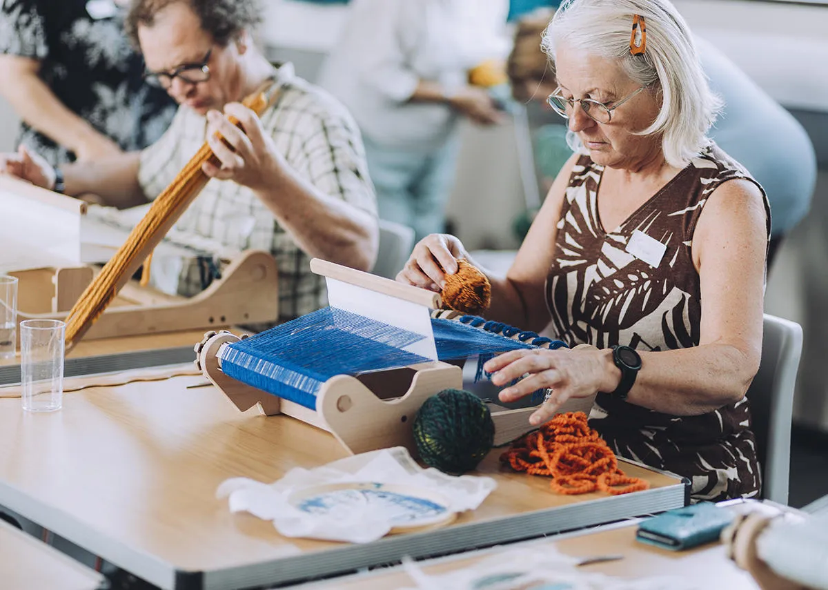 Two people practice weaving in a Risky Cities textiles workshop