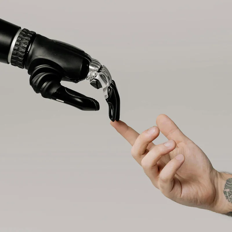 A robot hand and a human hand touch fingertips