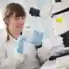 Student holding a petri dish at a microscope