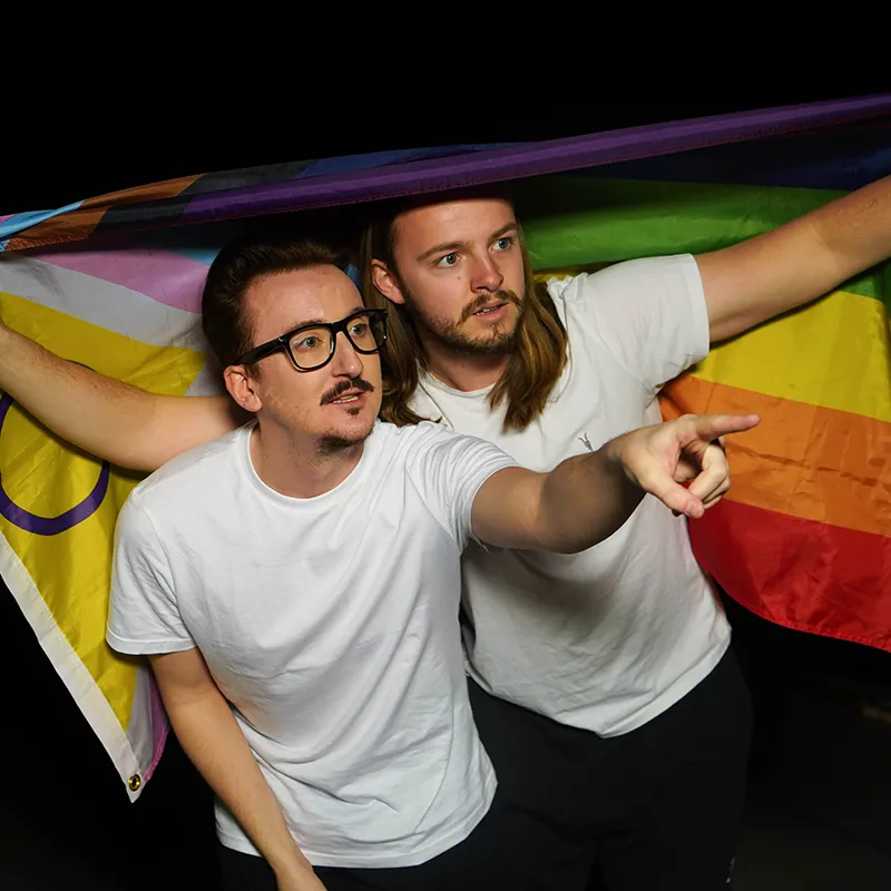 Two men holding a rainbow flag in the air