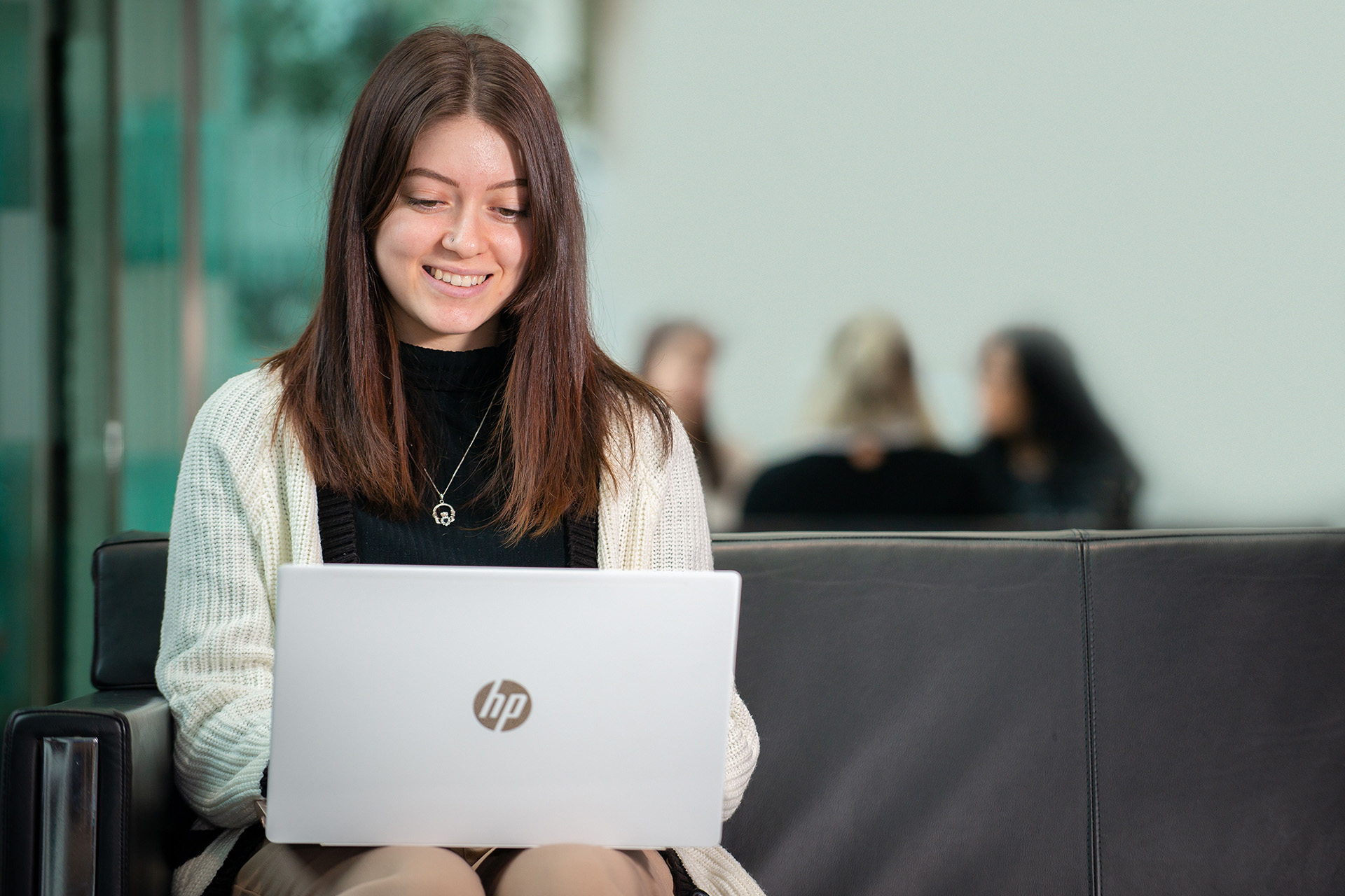 Student on laptop on leather sofa.