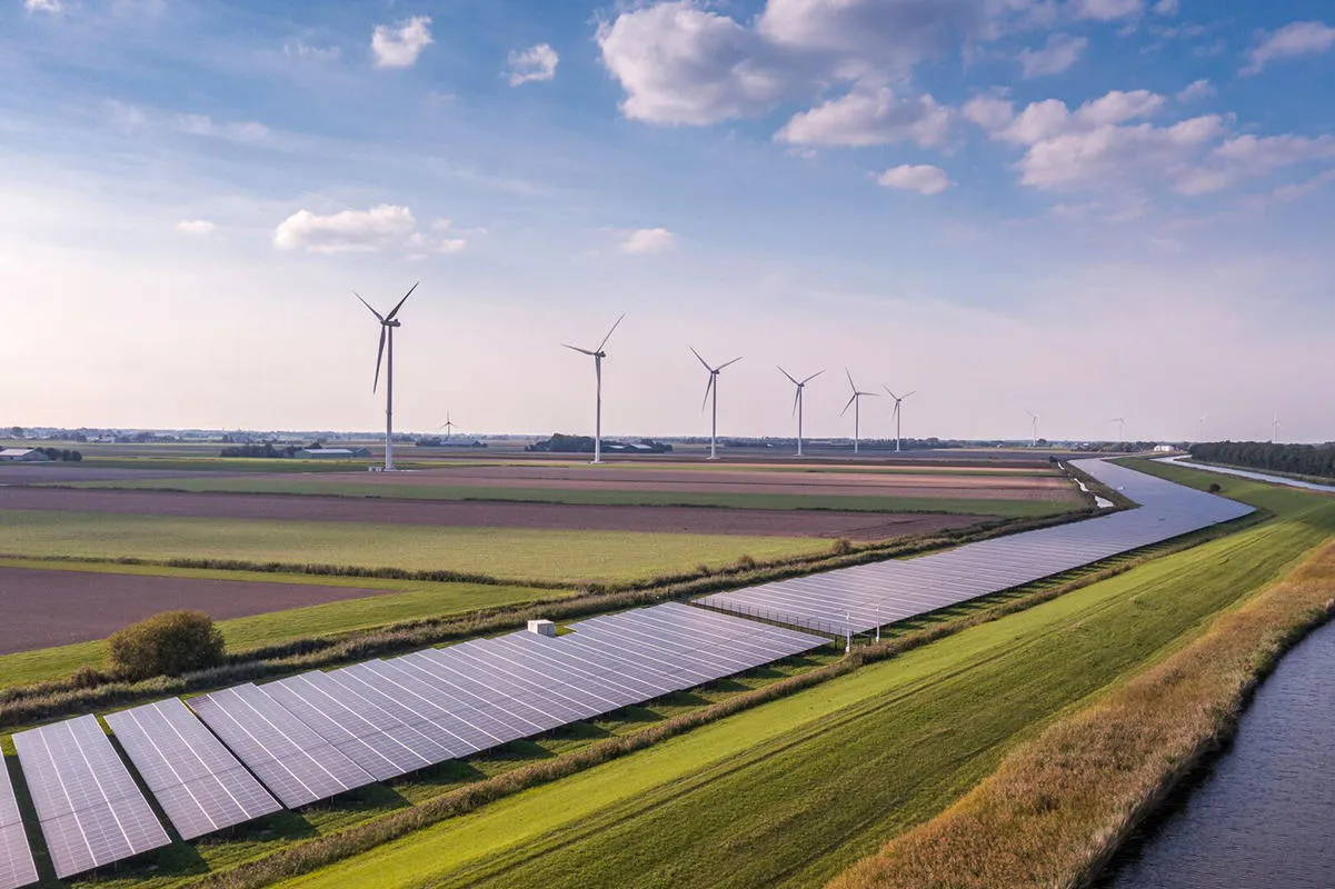 Solar panels and wind turbines in a green field