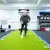 Man running or exercising on a green turf track in the Strength and Conditioning Suite.