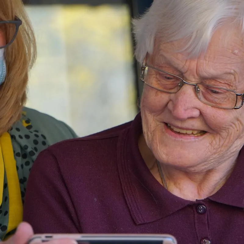 An elderly patient and a careworker review results on an iPad